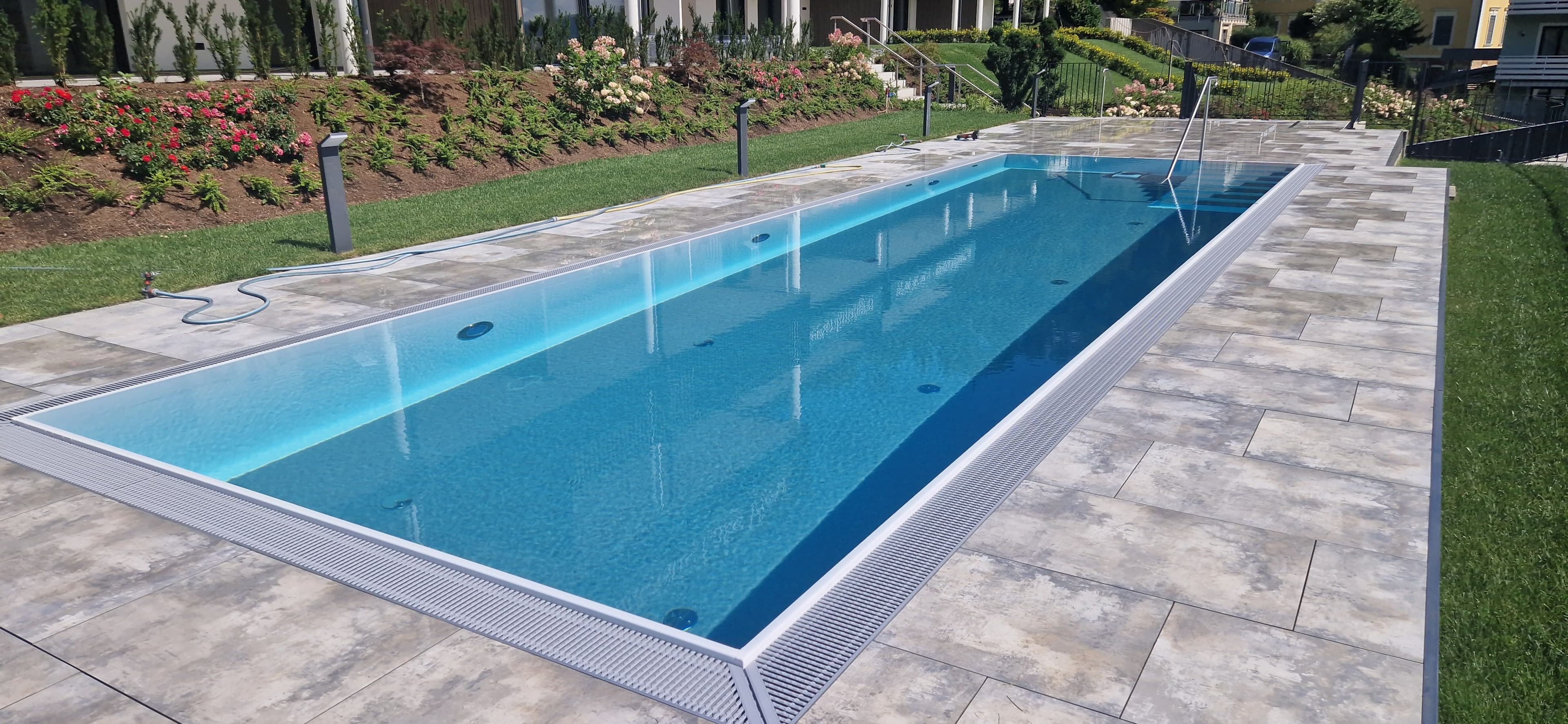 Überlaufpool im Garten mit umlaufendem Rinnenrost, das Wasser steht auf Höhe des Beckenrands