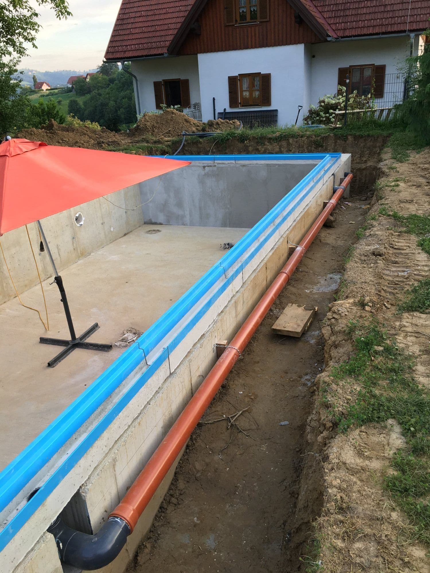 Einteilige Überlaufrinne mit integriertem Rinnenboden, montiert auf dem fertigen Poolrohbau mit verlegter Ablaufleitung